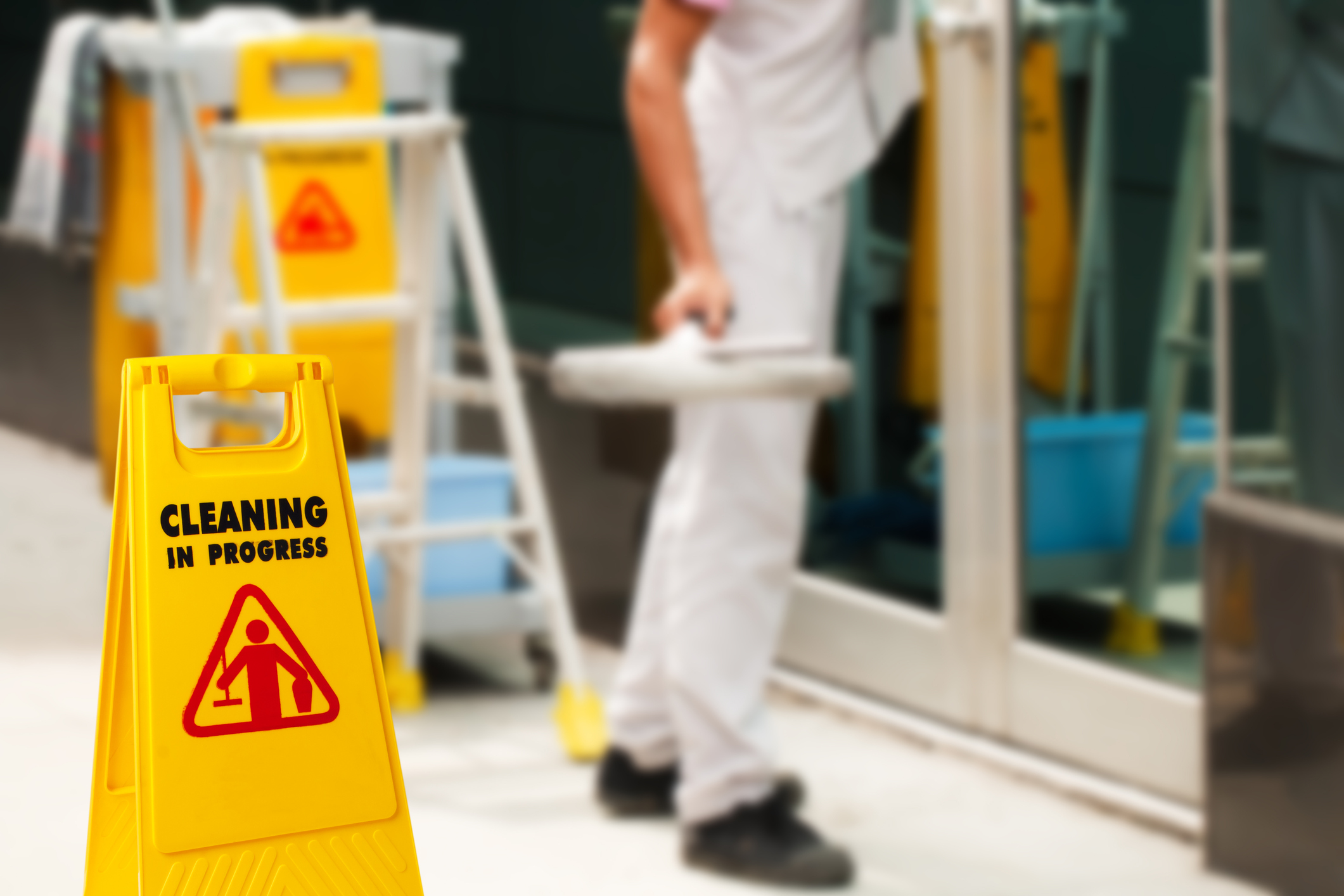 The warning signs cleaning in progress in the building and the janitorial mop bucket car parked and the maid working in the back. To remind people to walk safely.