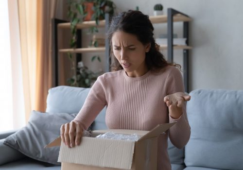 Angry confused woman unpacking parcel